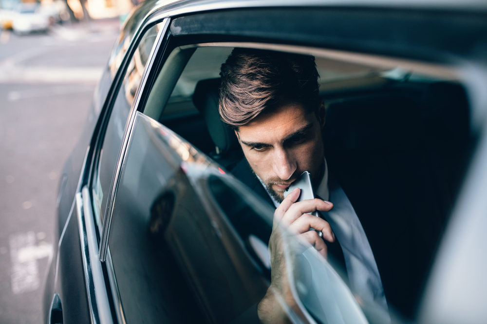 Man looking out window of car while taking an Uber to work