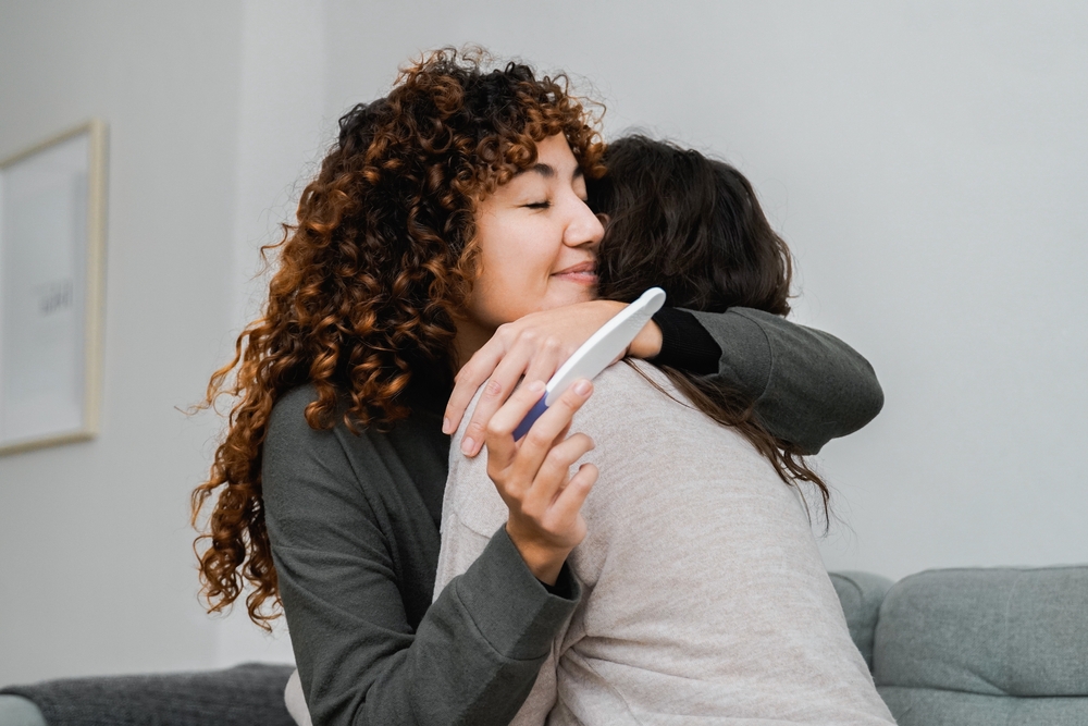 Friends hugging over a pregnancy test result