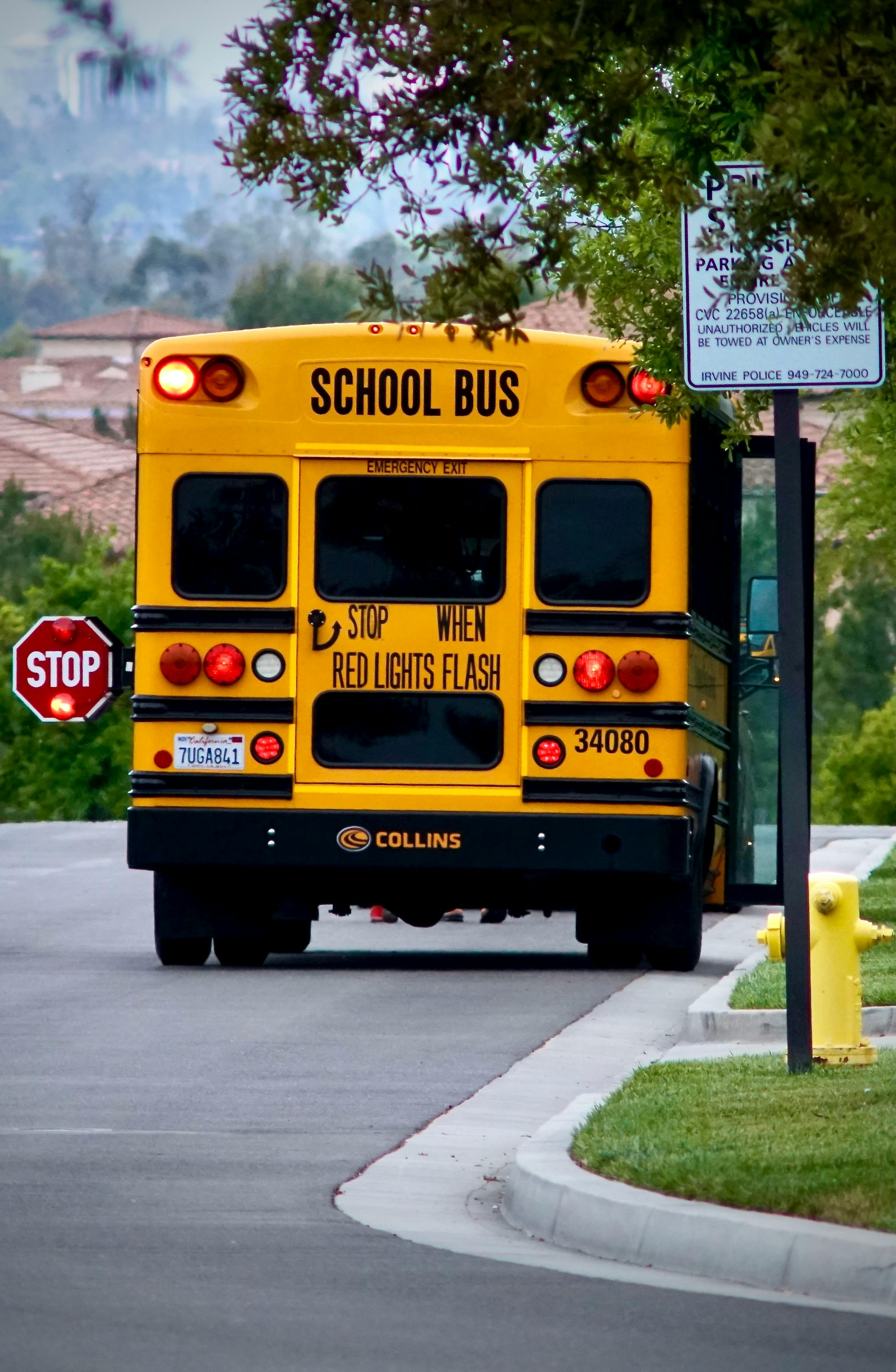 California school bus stopped with red flashing lights and children crossing during Back to School Safety Month 2025