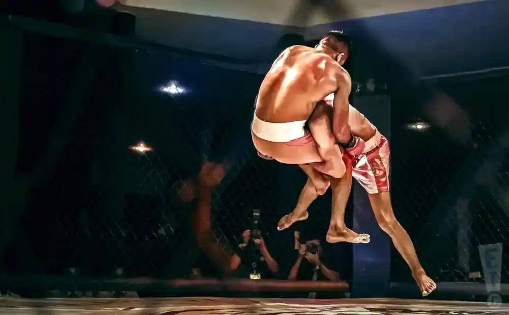 MMA fighter slams opponent in ring, audience watches.