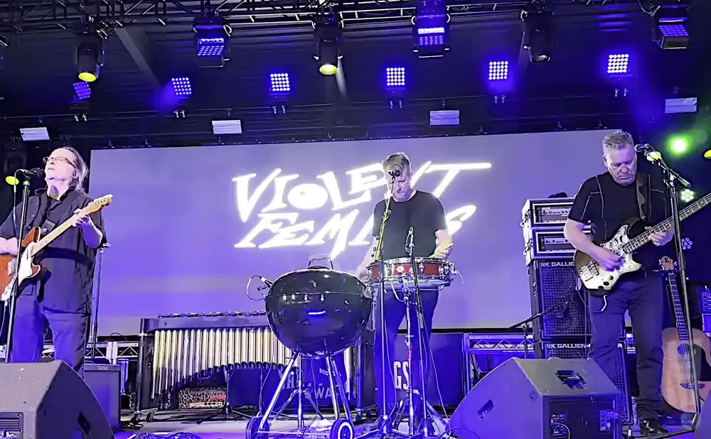 Violent Femmes performing live with band members playing guitar, bass, and drums.