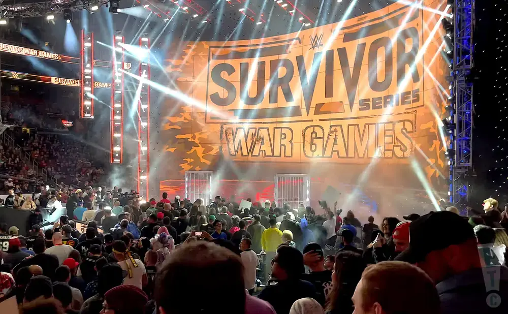 WWE Survivor Series War Games stage with bright lights and a crowd.