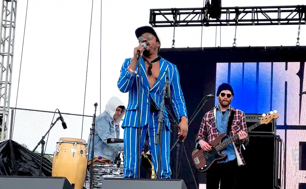 Band performing on stage with a lead singer in a blue pinstripe suit.