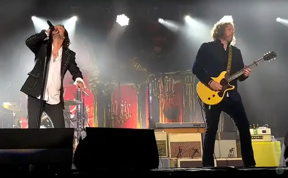 A singer on stage with a microphone and a guitarist playing a yellow guitar.