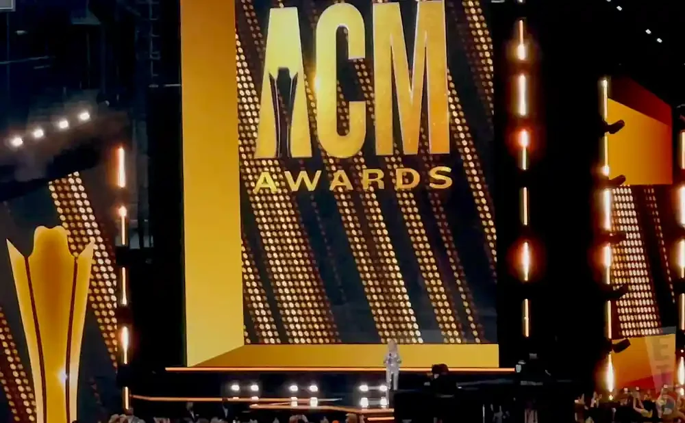 ACM Awards stage with large gold lettering and a spotlighted performer.