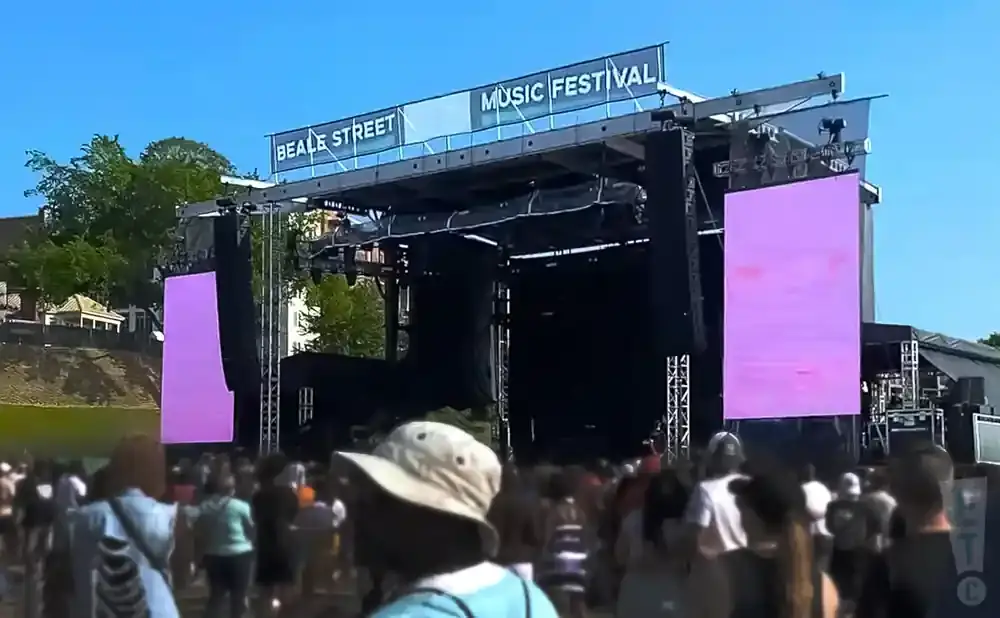 A music festival stage with large purple screens and 