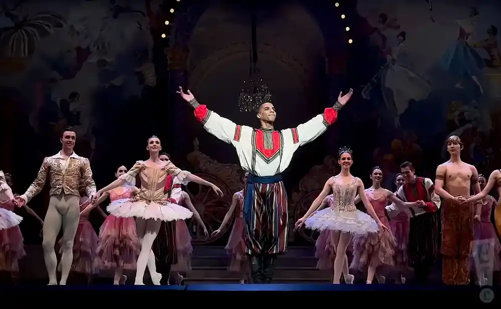 Ballet dancers in elaborate costumes perform on stage.