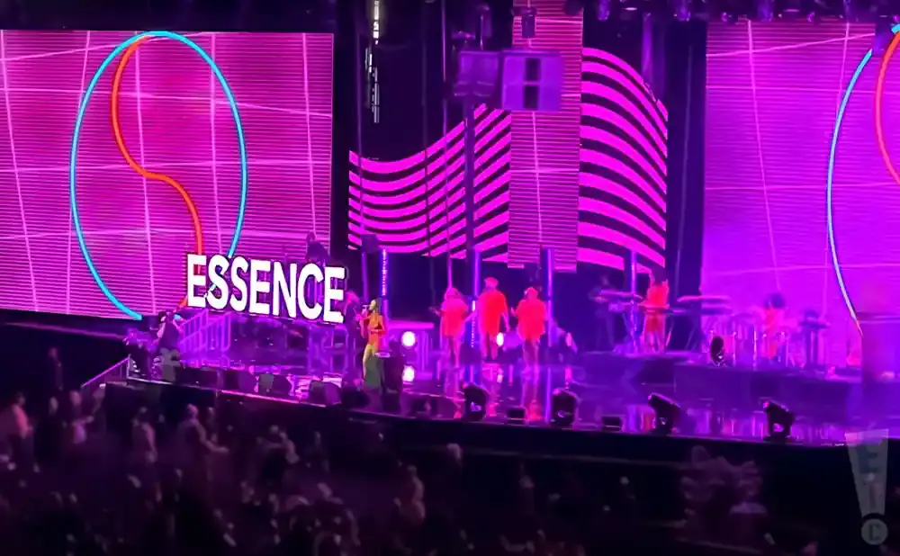 A woman in a green dress sings on stage with the word 