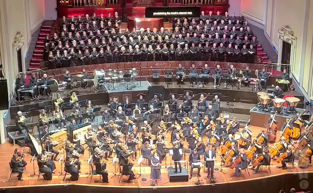 An orchestra and choir perform on a stage.