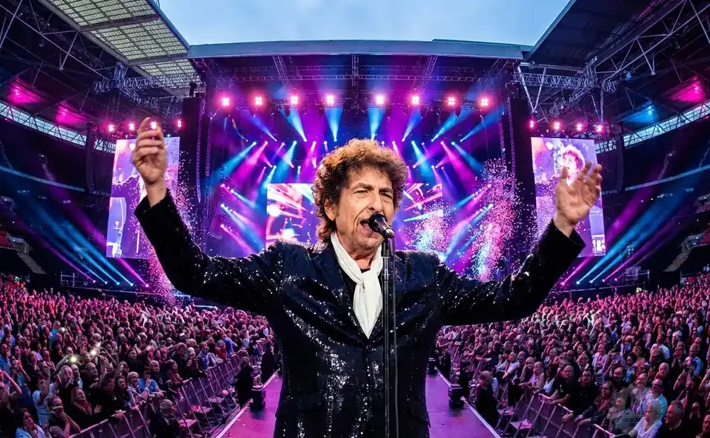 Bob Dylan in a hat plays a piano on stage with another musician.