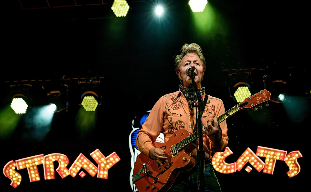 Guitarist plays on stage under bright lights with 