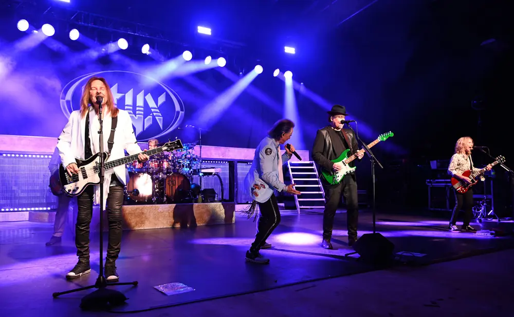 A band performs on stage with blue lights and fog.