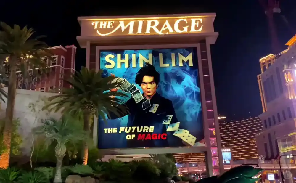 A billboard for Shin Lim's magic show at The Mirage, featuring his portrait and playing cards.