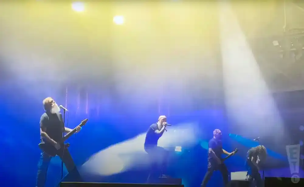 Band performs on stage under bright yellow and blue lights.