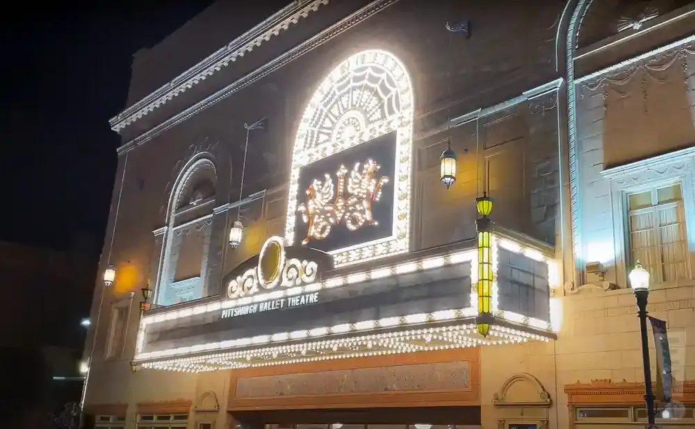 Exterior of Pittsburgh Ballet Theatre at night, illuminated by marquee lights and building spotlights.