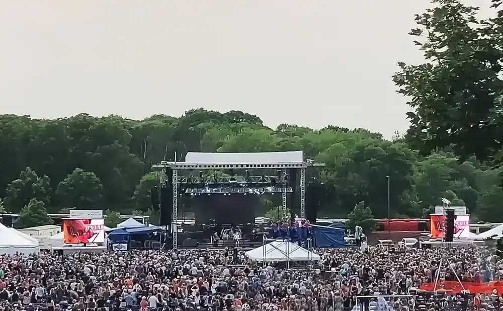 A crowded outdoor concert with a large stage and a dense audience.