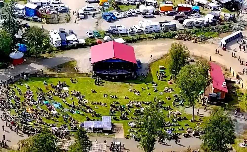 An aerial view of an outdoor concert with a large crowd gathered on a grassy field.