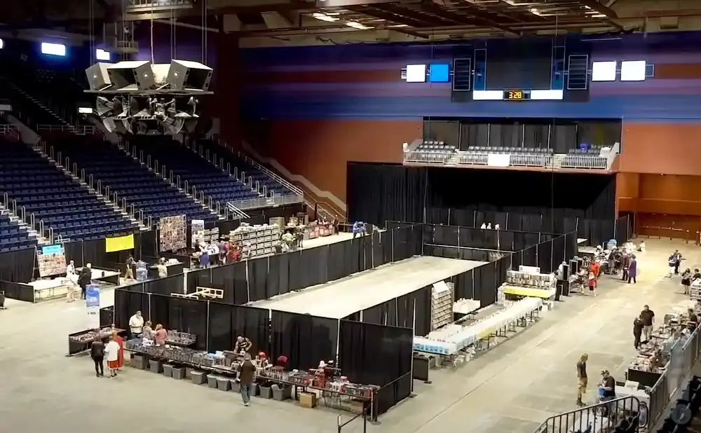 An indoor marketplace in an arena with booths and people.