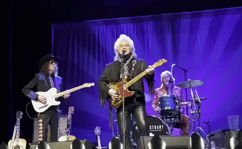 Marty Stuart and His Superlatives perform on stage with Marty playing guitar and singing.