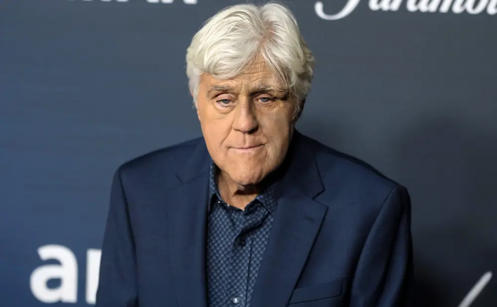 Jay Leno in a dark blue suit and patterned shirt.