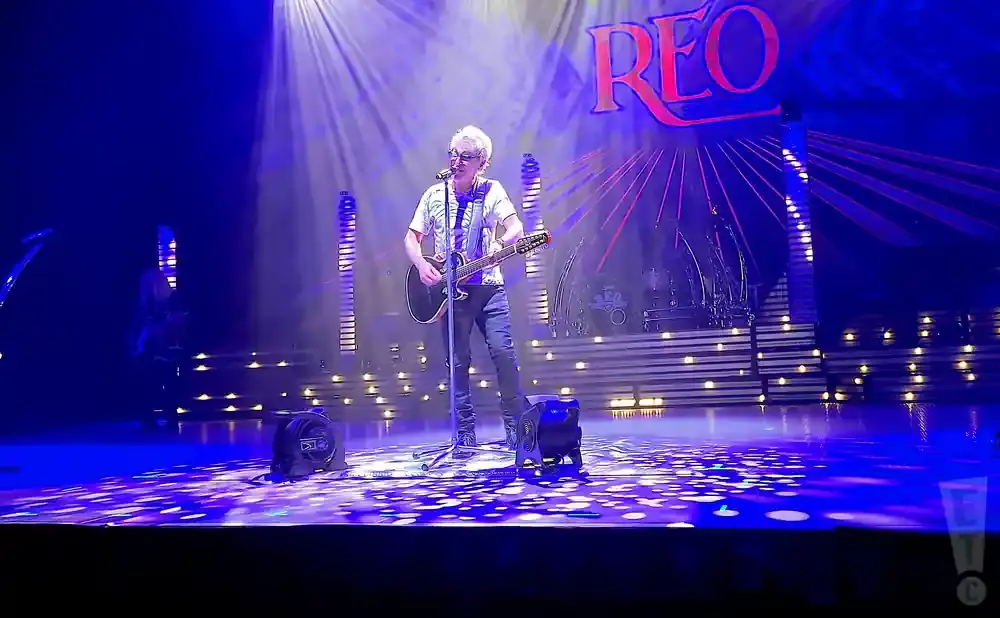 Musician playing guitar and singing on stage with 