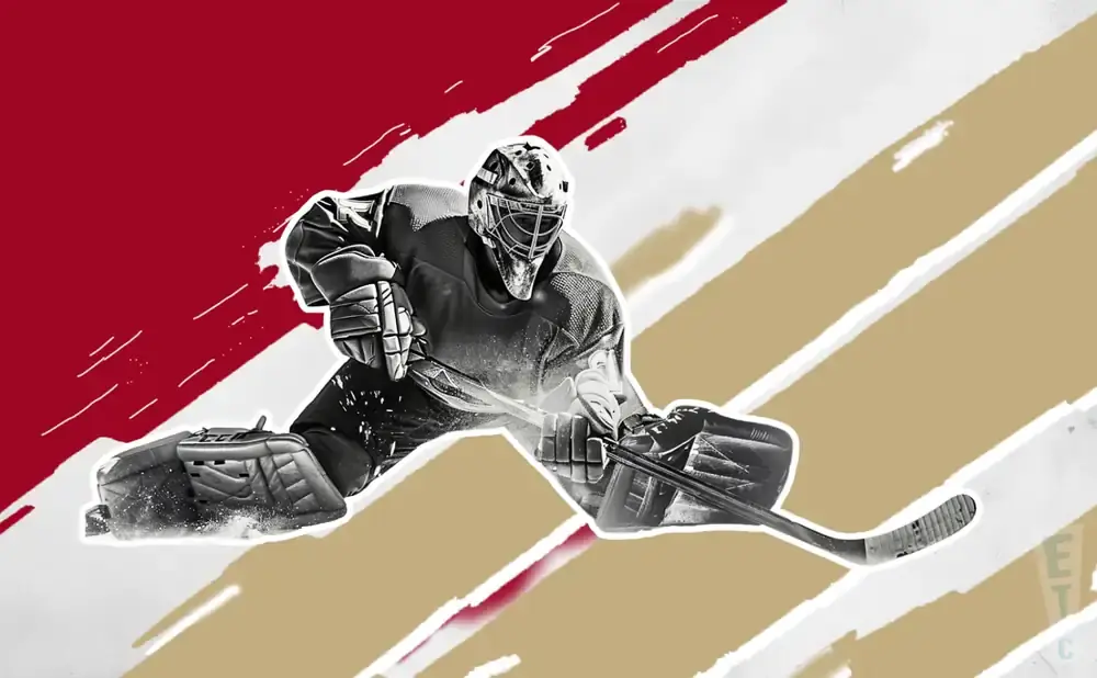 A hockey goalie in full gear slides to make a save, with a stick in hand.