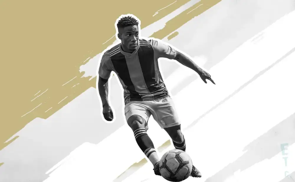 Black and white image of a soccer player in action, dribbling a ball.