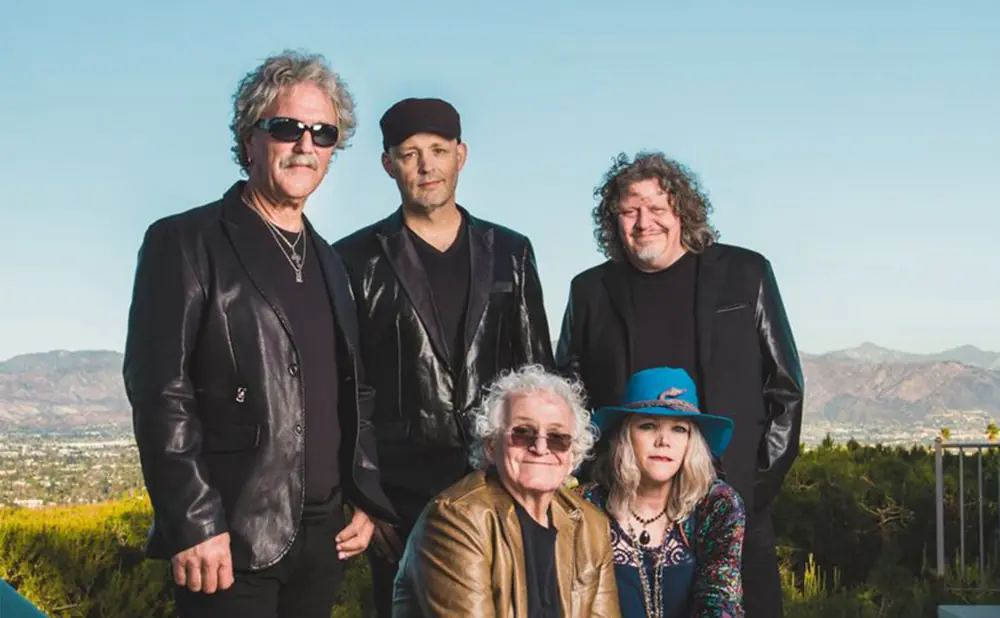 Five people posing for a photo with a landscape in the background.