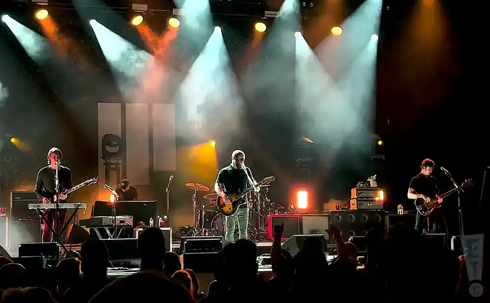 A rock band plays on a dimly lit stage with bright spotlights.