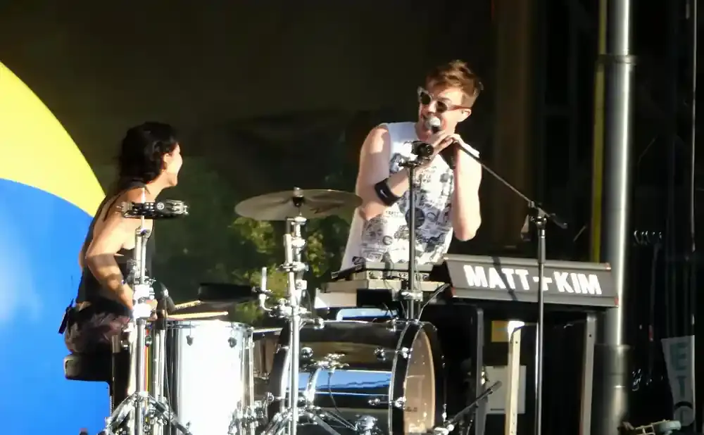A drummer and a keyboardist perform on stage.