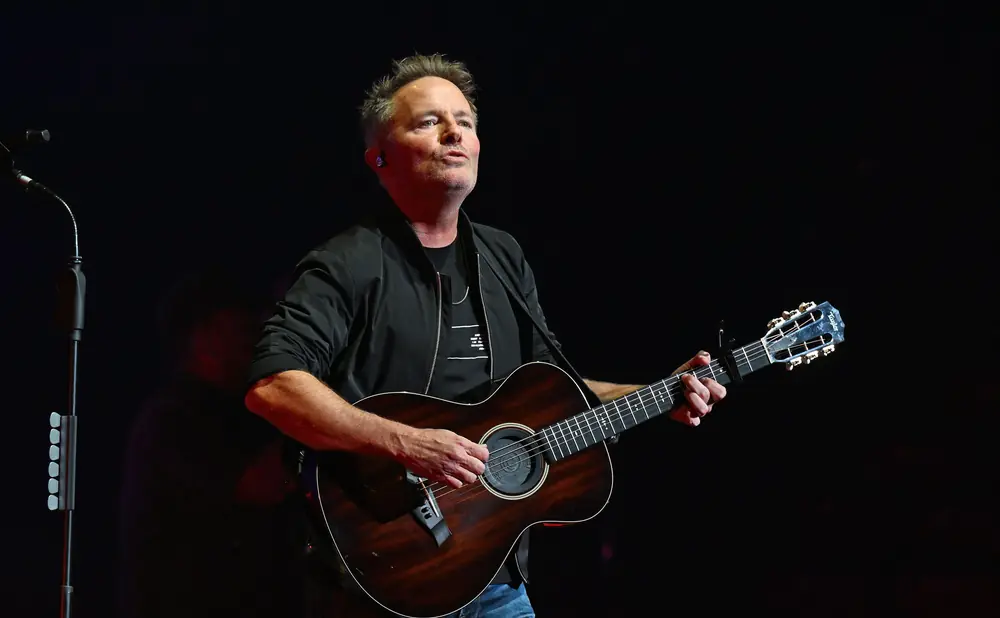 Man playing acoustic guitar on stage.