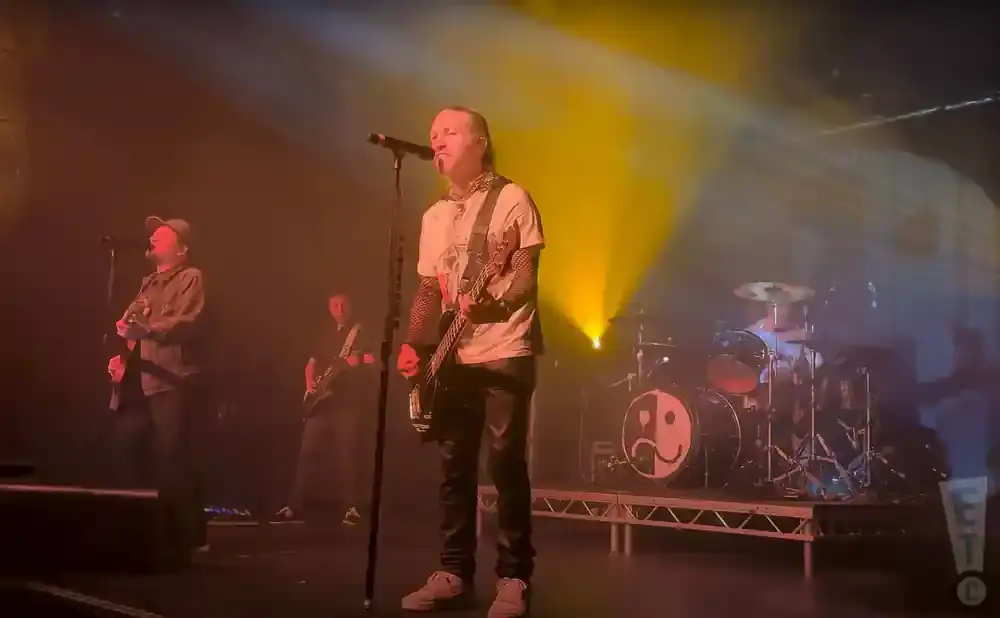 Band playing on stage with yellow spotlights, drummer in the background.
