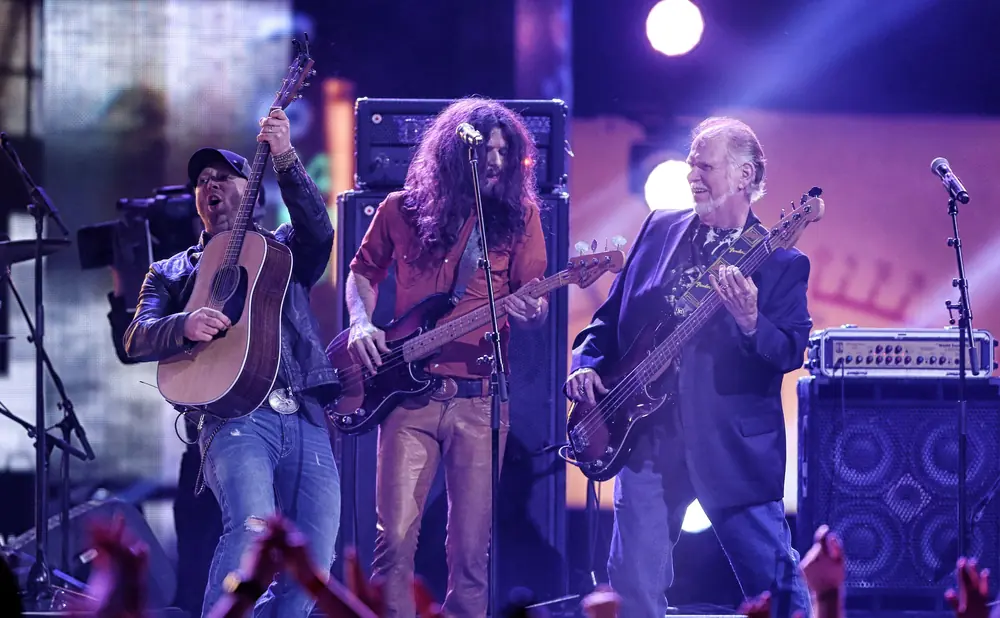 A band performs on stage, with three musicians playing guitars.