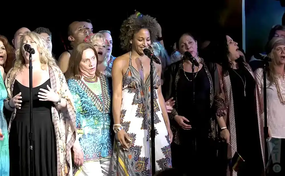 A diverse group of singers performing on stage at night.