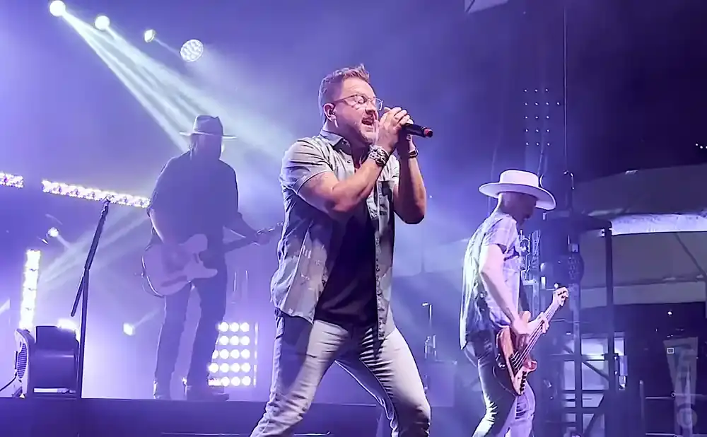 A band performs on a brightly lit stage with purple and white lights.