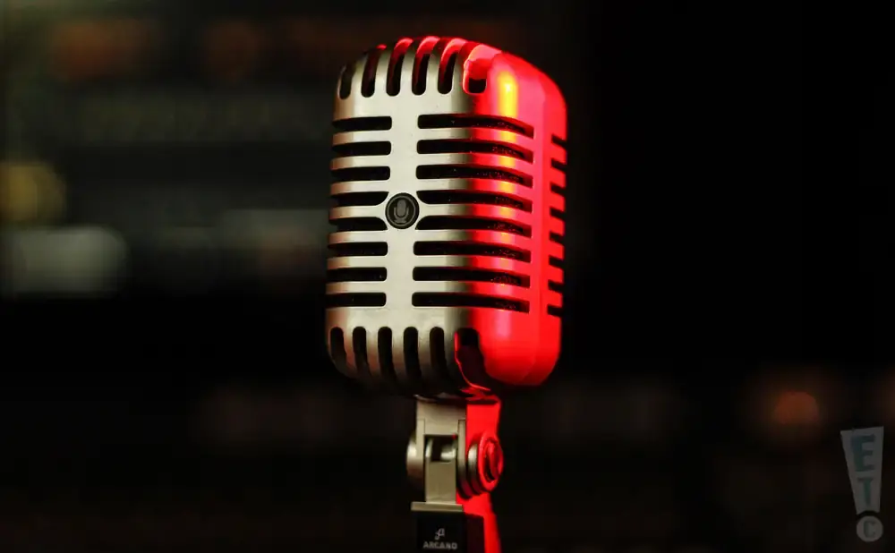 A retro silver microphone with a red spotlight, on a black background.