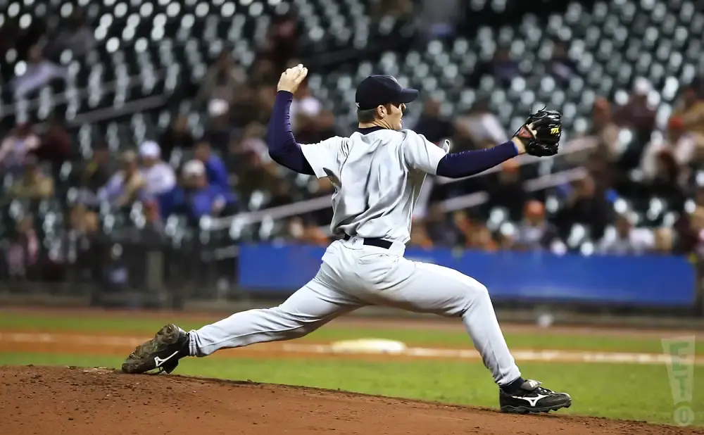 A baseball pitcher in a grey uniform throws a pitch during a game.