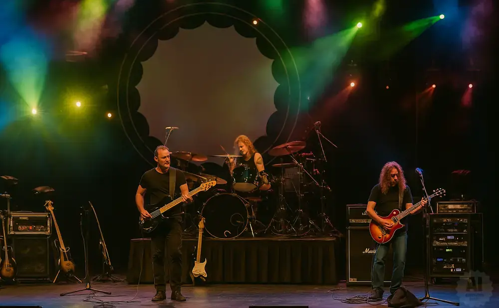 A band performs on stage with colorful spotlights illuminating the musicians.