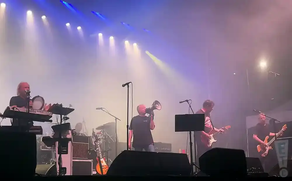 A band performs on a brightly lit stage with fog.