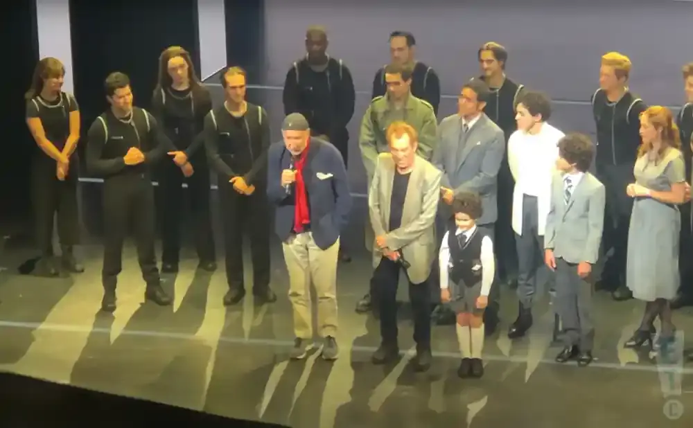 A diverse group of actors stand on a stage.