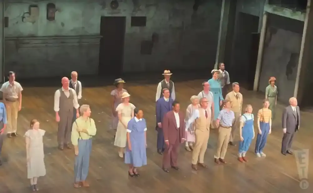 A group of actors in vintage clothing stand on a stage.