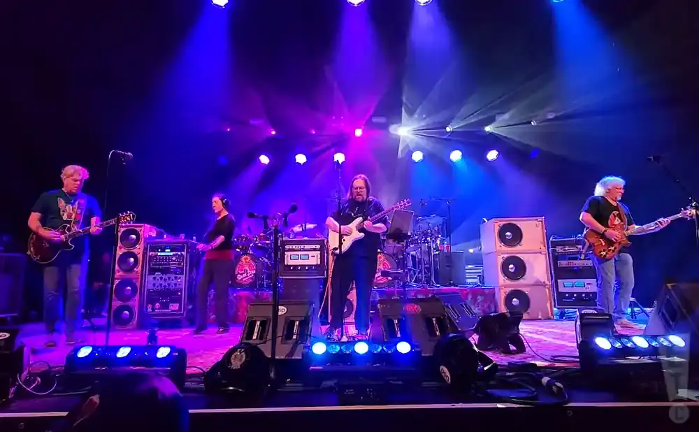 A band plays on a brightly lit stage with purple and blue lights.