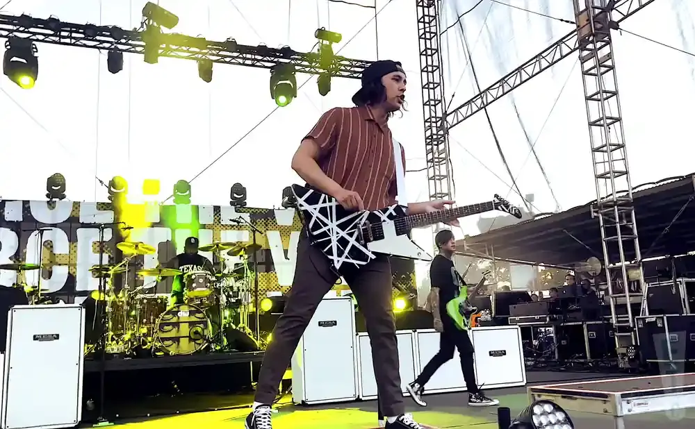 A band performs on a stage with yellow lighting.