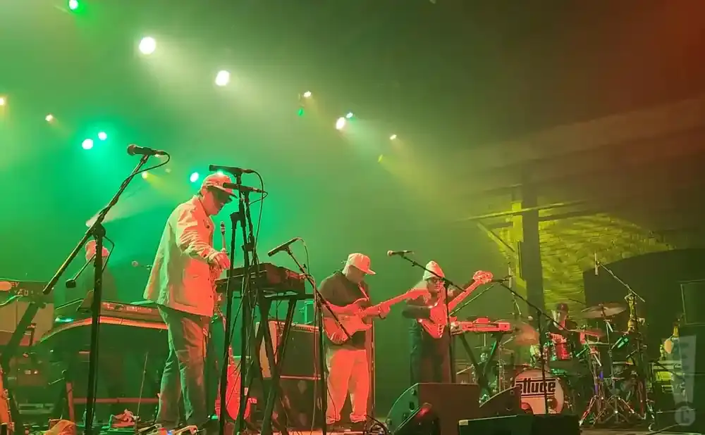 A band performs on stage with green and orange lighting.