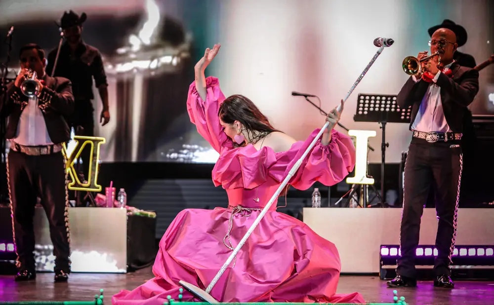 Singer in a pink gown on stage with mariachi musicians.