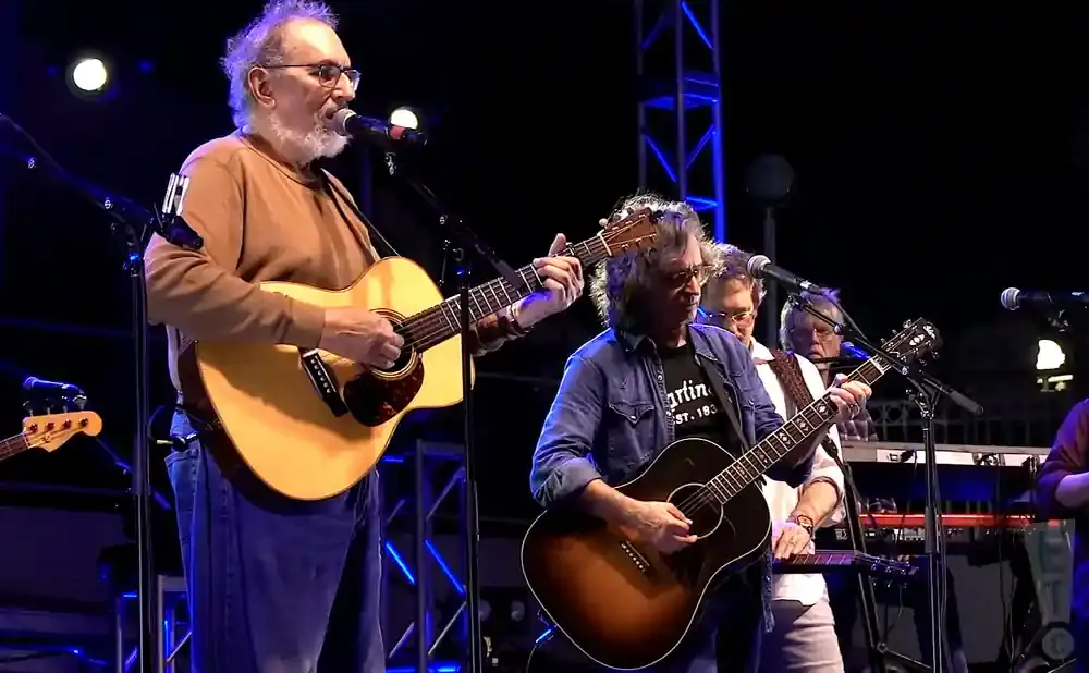 Men playing guitars on stage at a concert.