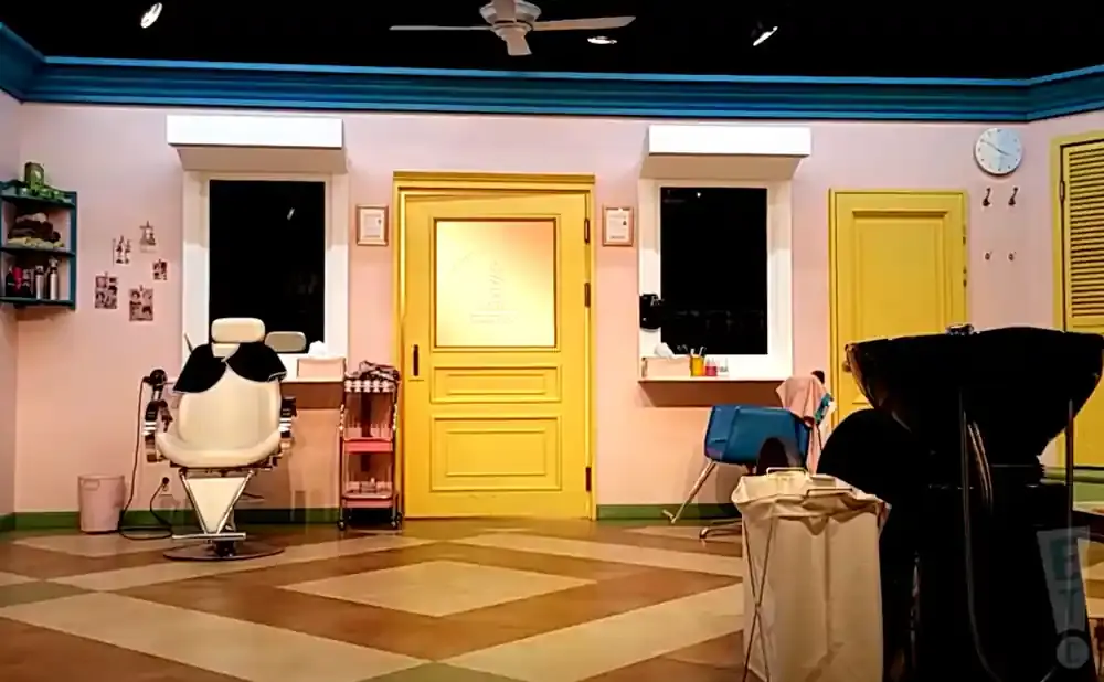 A bright salon with a yellow door, white salon chair, and a shampoo bowl.