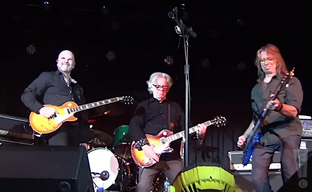 A band plays guitars on stage.