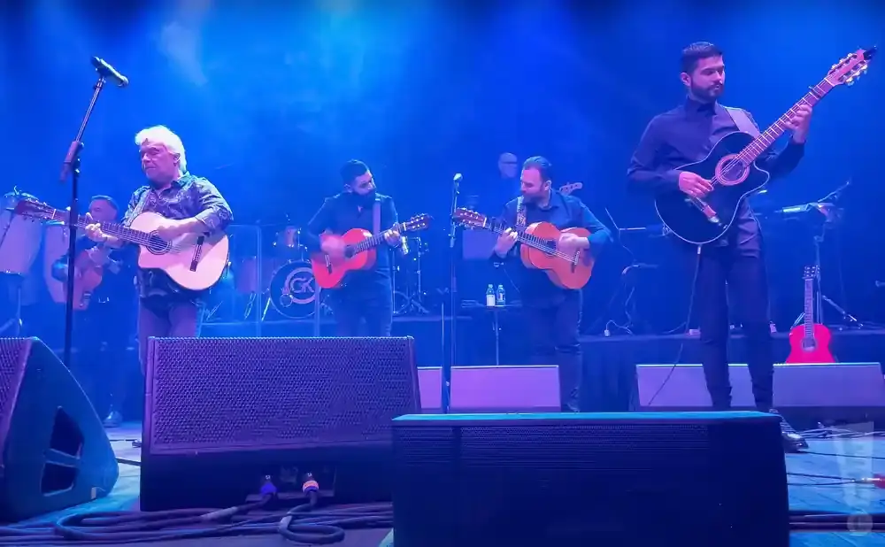 A band plays guitars on a brightly lit stage.