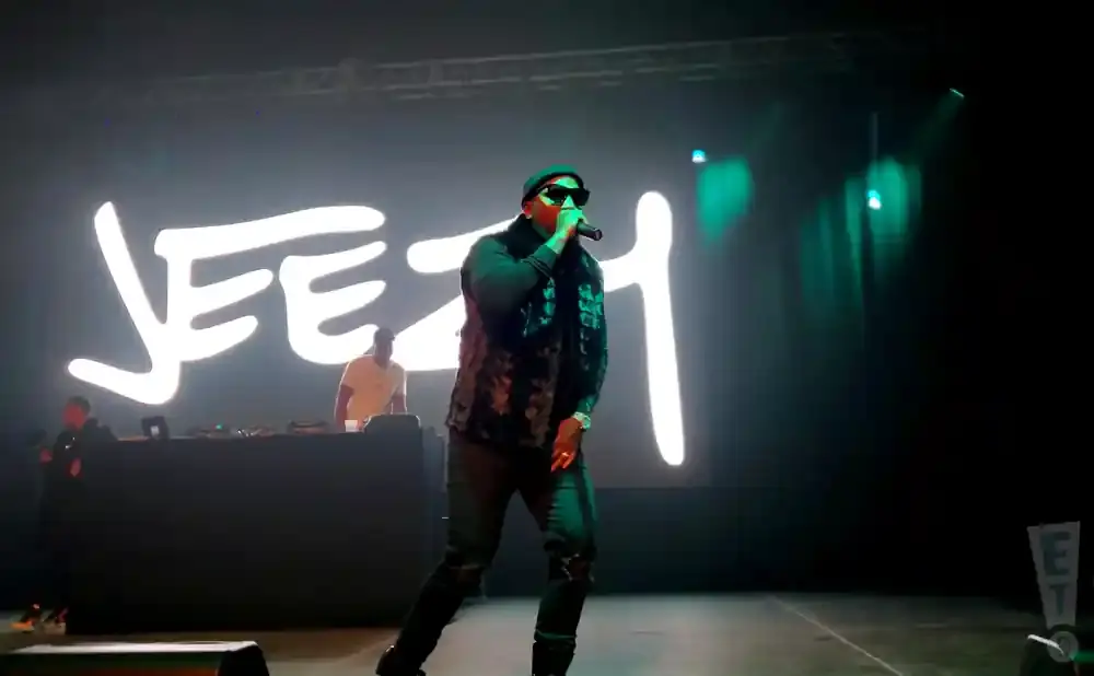 A rapper performs on stage in front of a large 